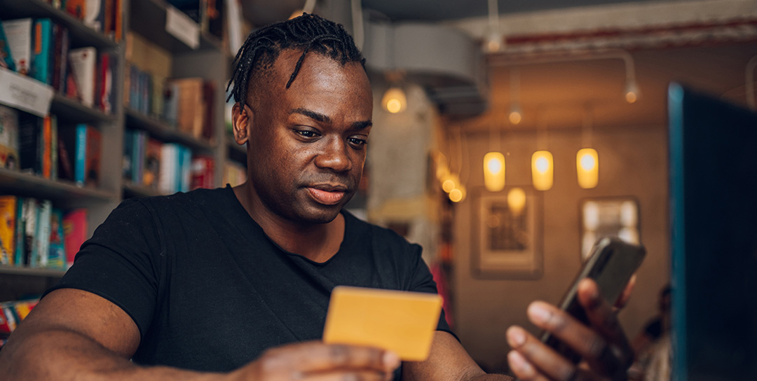 Guy looking at credit card and phone.