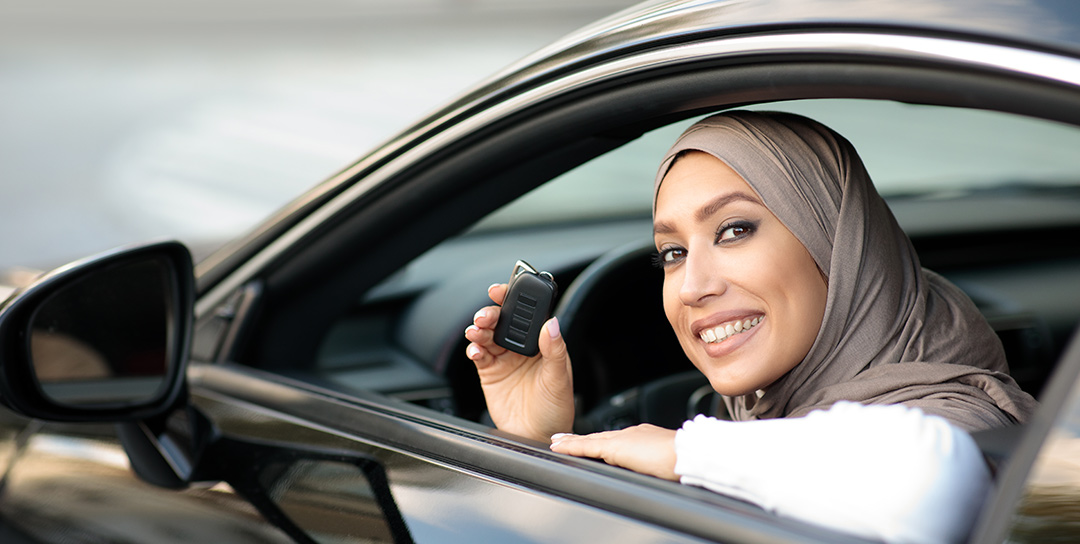 Girl with a hajib and key fob leaning out a car window.
