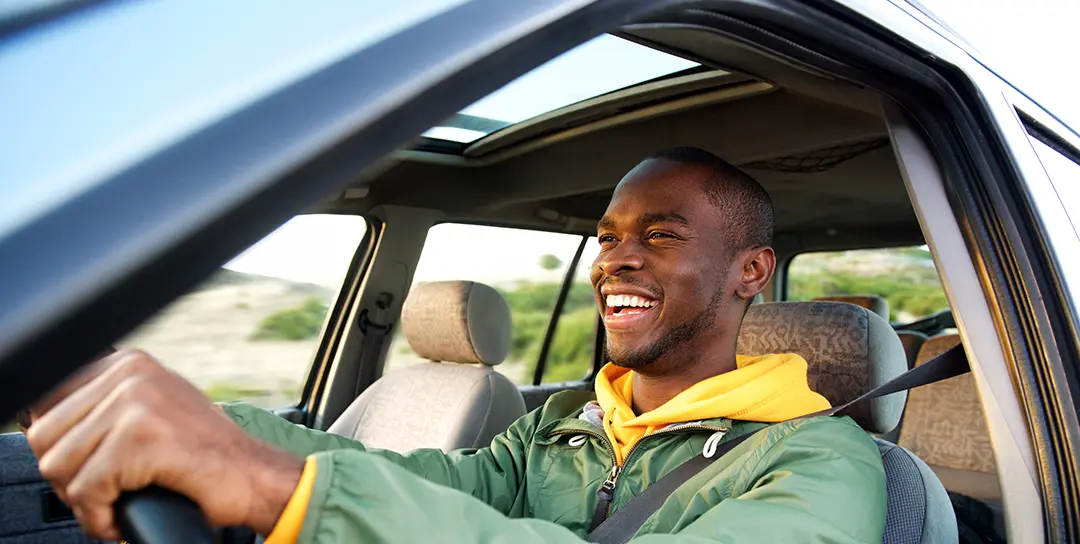Man driving and smiling alone in car.