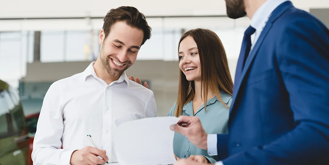 Family couple buying auto while man signing contract.