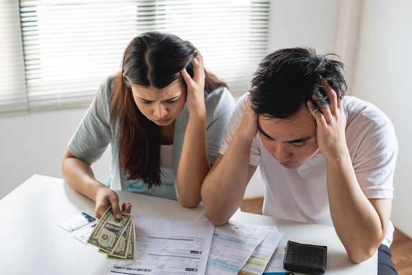 A worried couple examines bills and money, debt concept.
